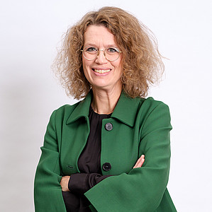 Abgebildet ist Prof. Dr. Anrea Wechsler, Präsidentin der Europa-Union Deutschland, mit braunen lockigen Haaren, einer Brille und einem grünen Mantel. Sie hat die Arme verschränkt. 
